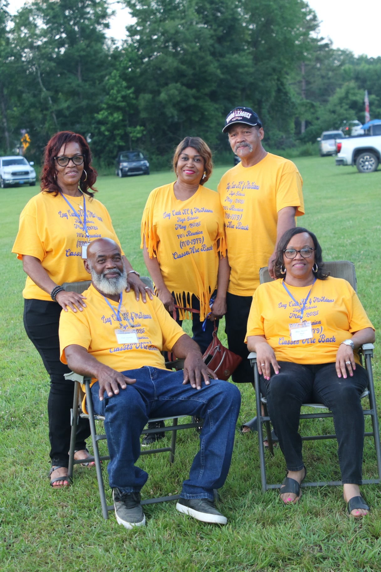 Five classmates in gold 70s Reunion tees posed on the lawn