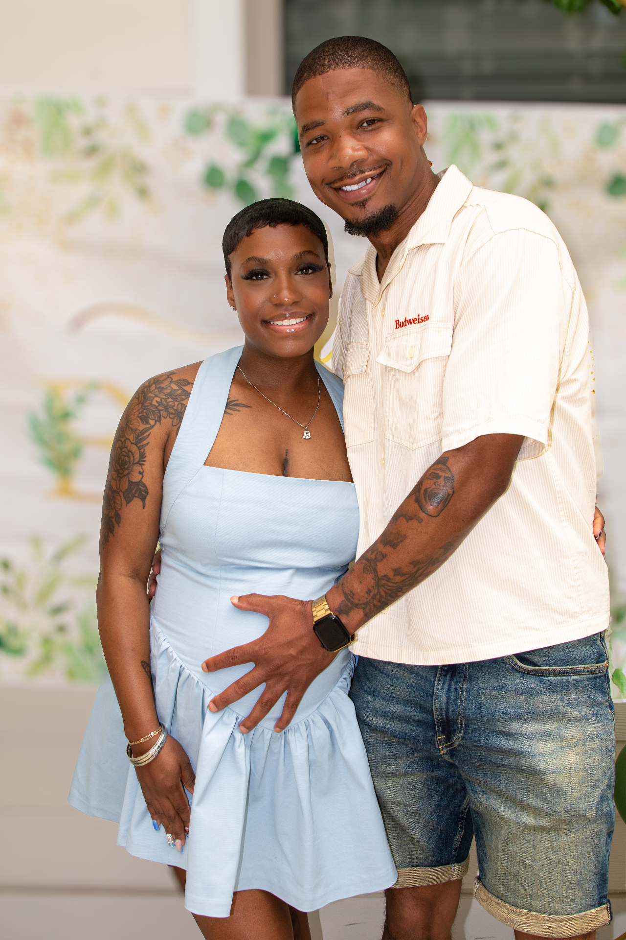 Couple posing at baby shower backdrop